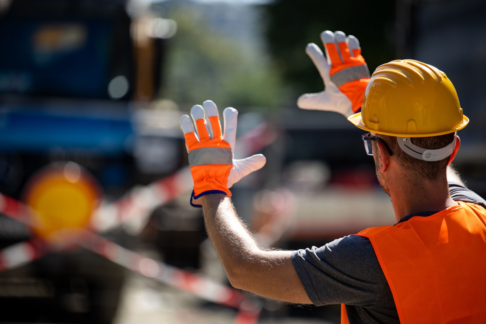 Construction worker directing traffic at a busy site in the afternoon under clear skies during ongoing repair work